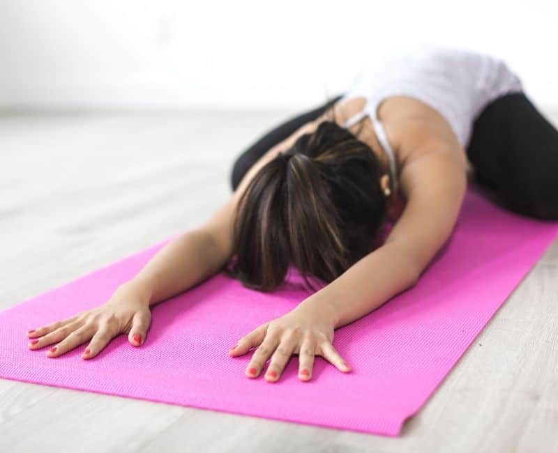 woman stretching on a pink yoga mat