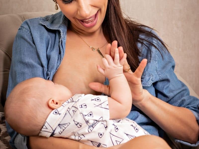 a woman nursing a baby in a blue shirt