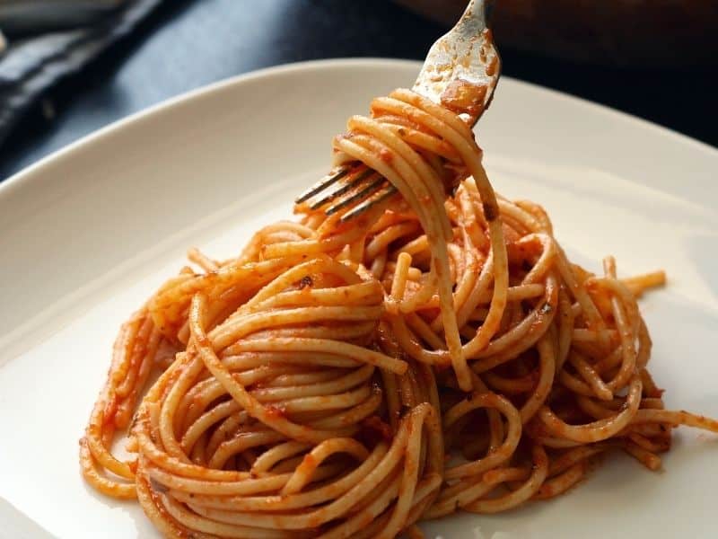 a plate of spaghettis with red sauce and a fork twirling it