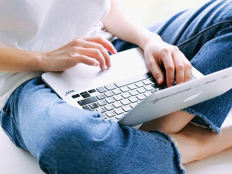 a woman sitting crossed legged typing on a laptop