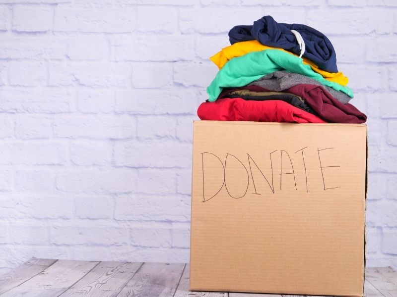 a paper bag with clothes stacked in and the words donate outside