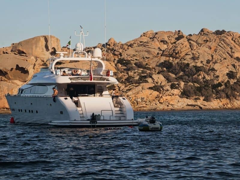 a yacht in the water with rocky hills in the background