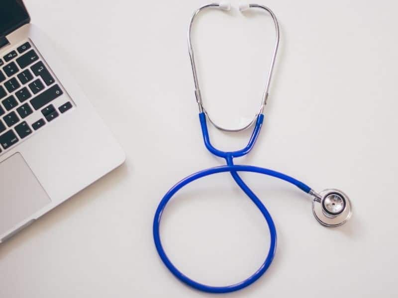 a blue stethoscope sitting on a table next to a laptop