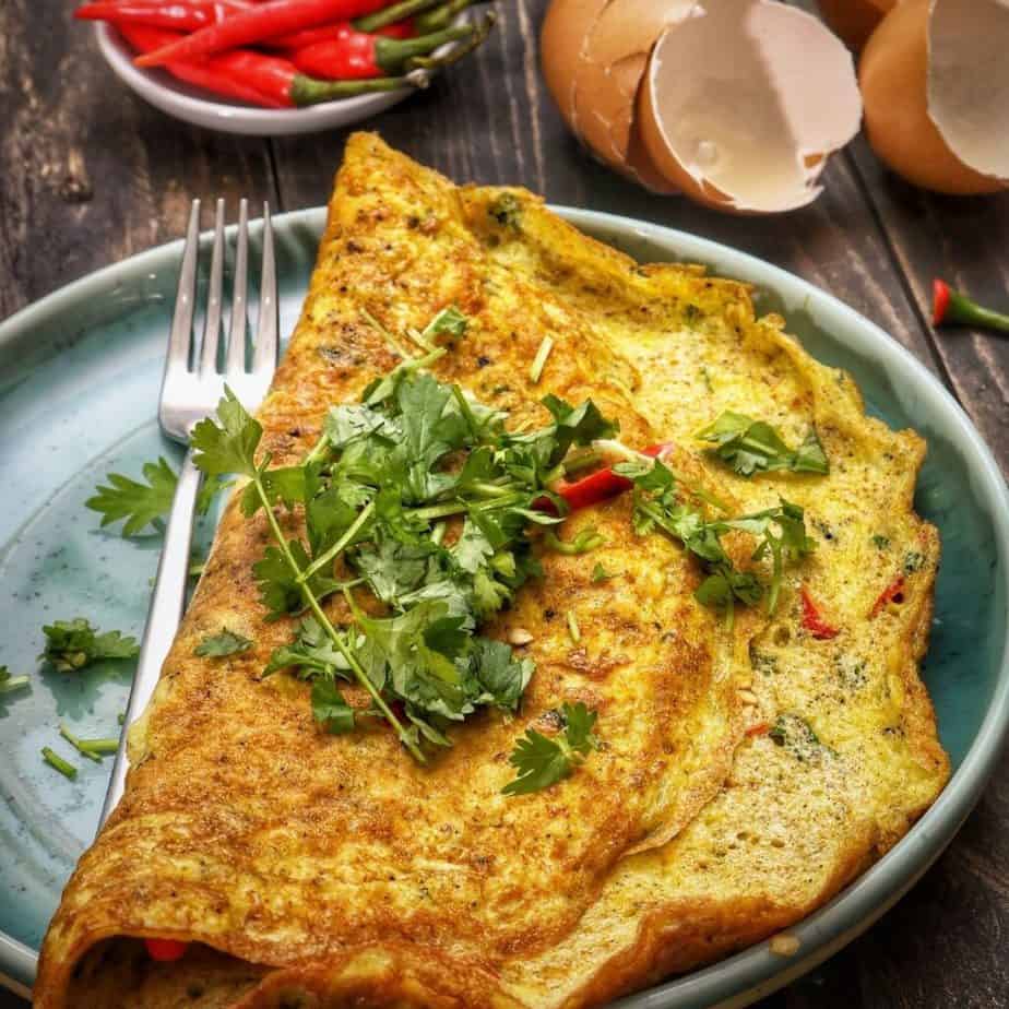 an omelet on a plate with cilantro garnish