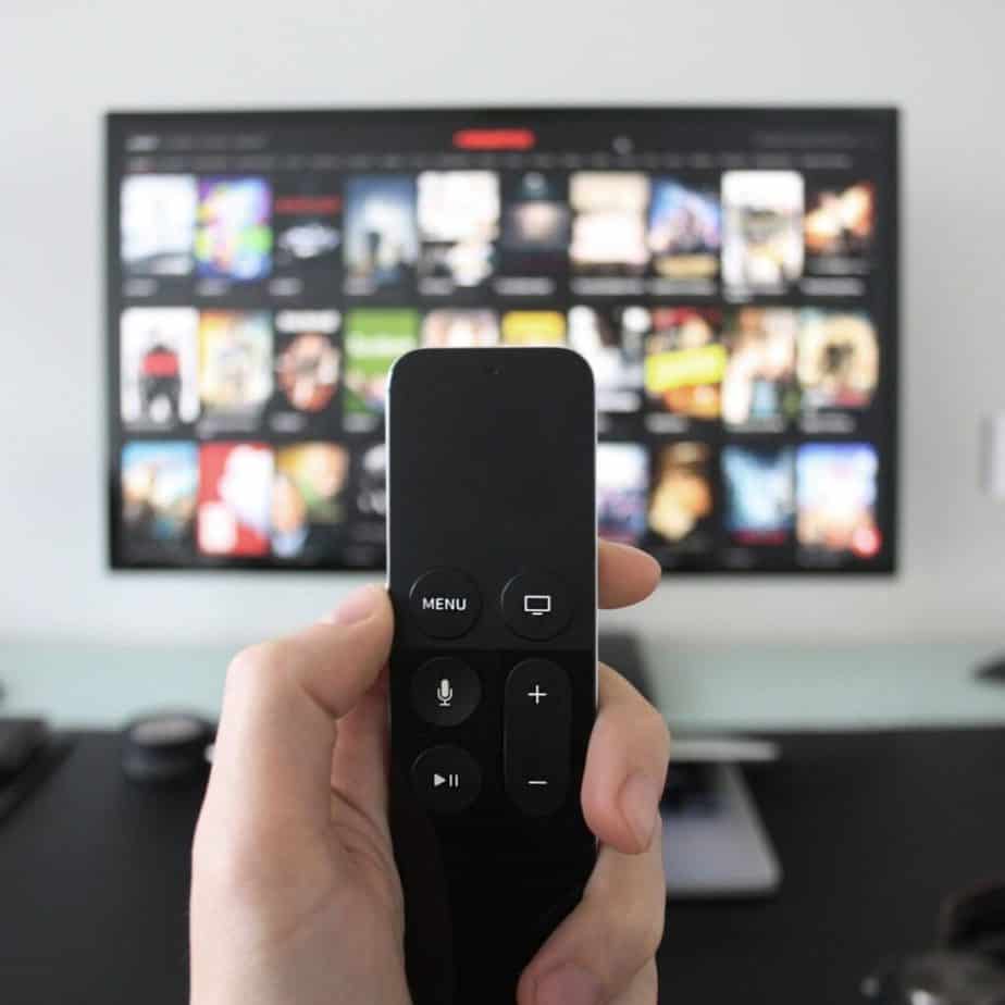 a hand holding a remote control in front of a tv screen