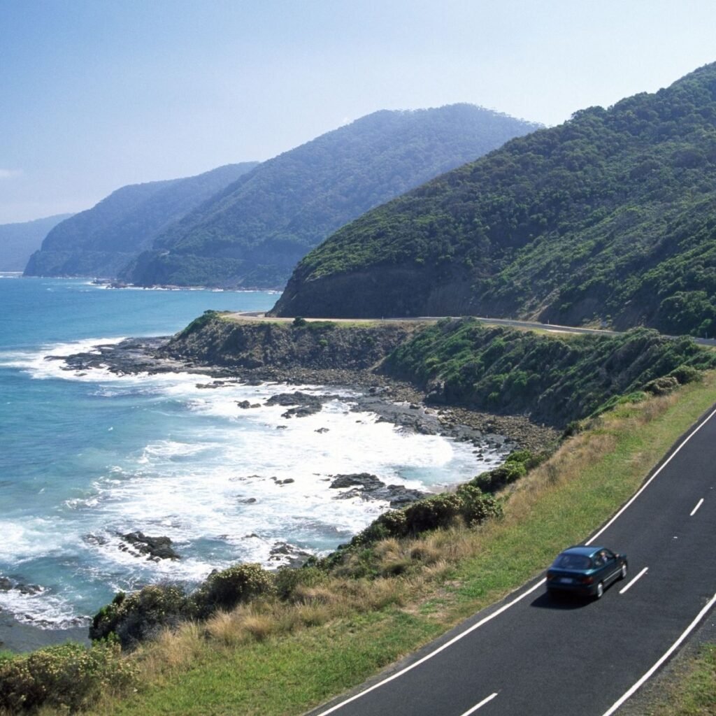 a car driving on a road along seaside cliffs
