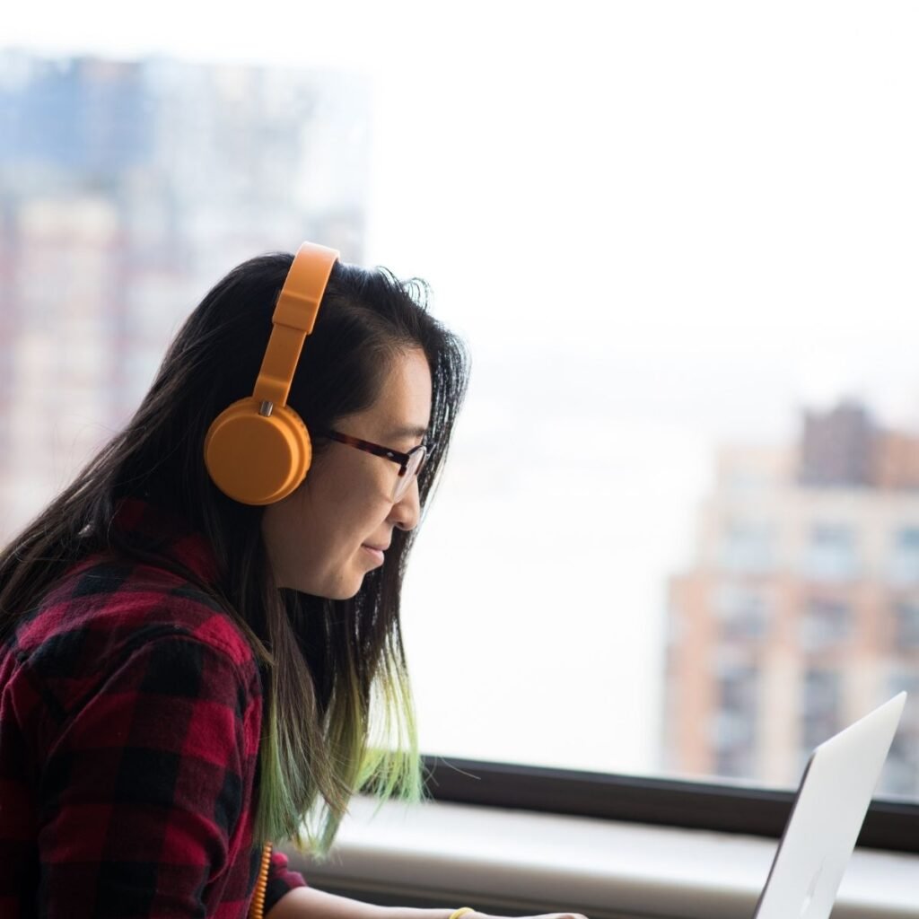 a woman wearing headphones looking at a laptop
