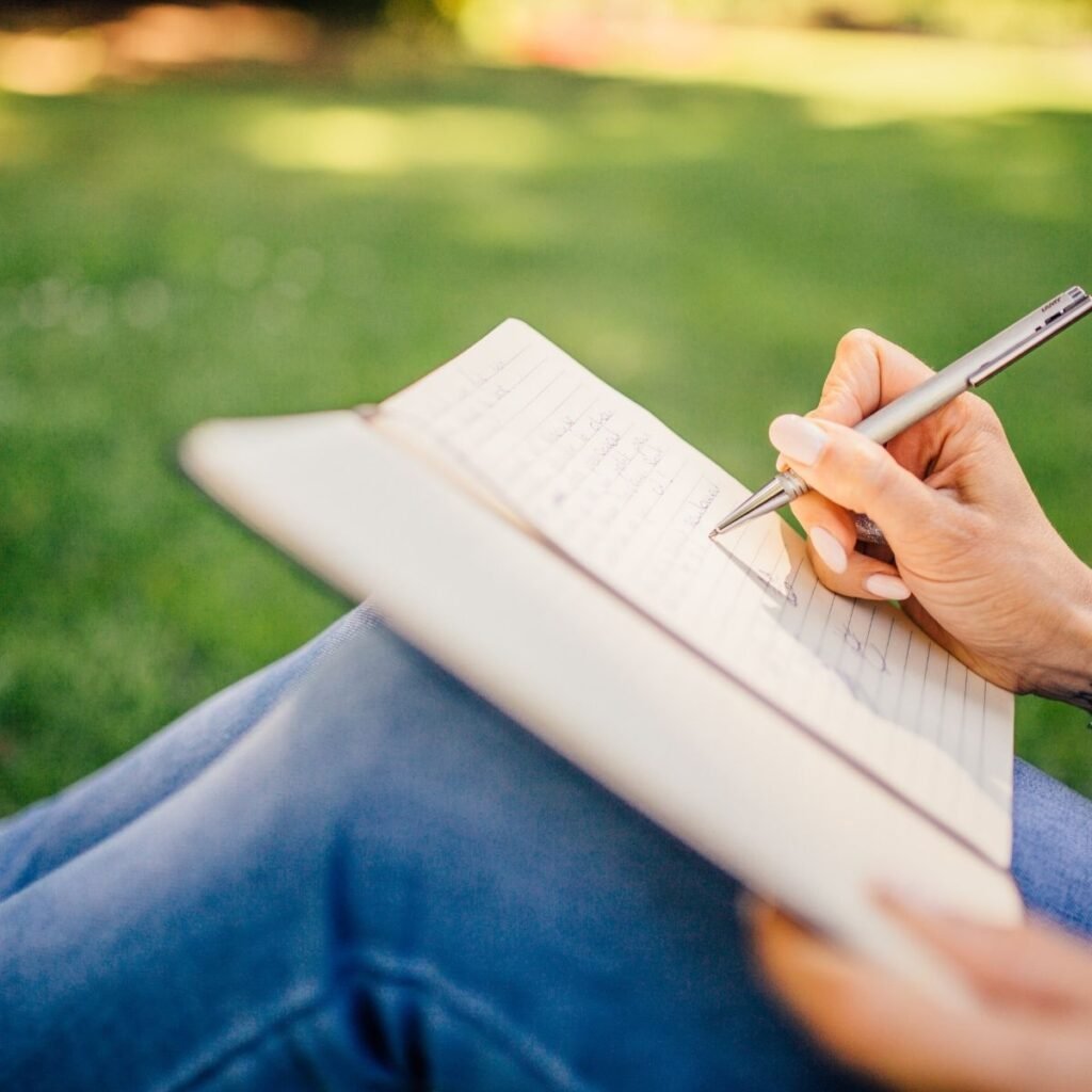 writing on a notebook on a lap in the grass