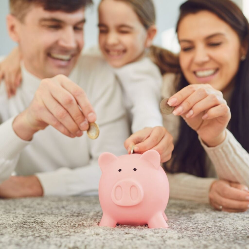 a family putting money in a pink piggy bank