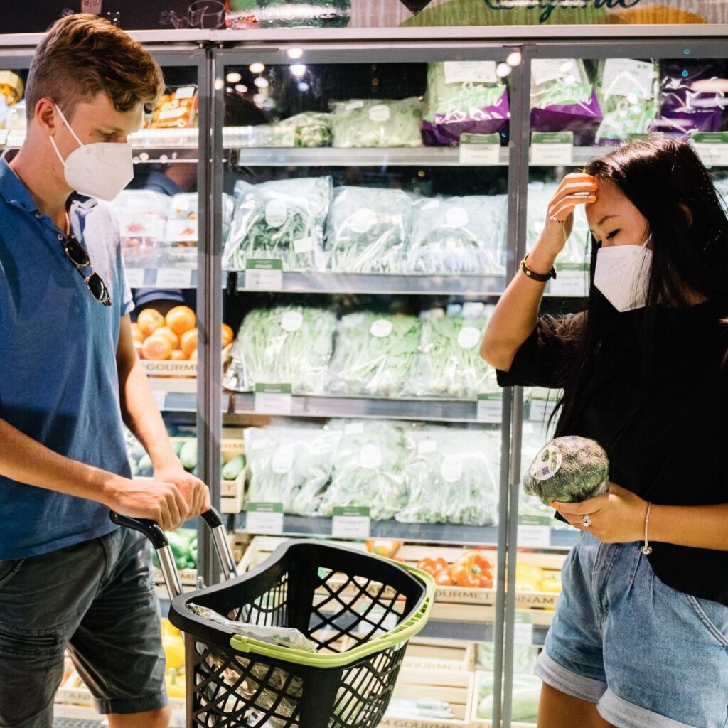 2 people standing in a grocery store with a basket