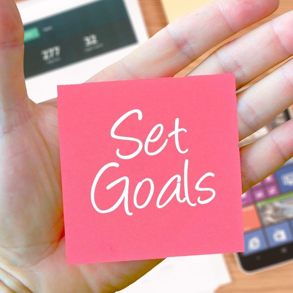 hand with a sticky note saying "set goals"