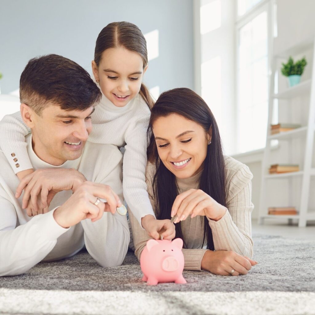 a family putting money in a piggy bank on a counter