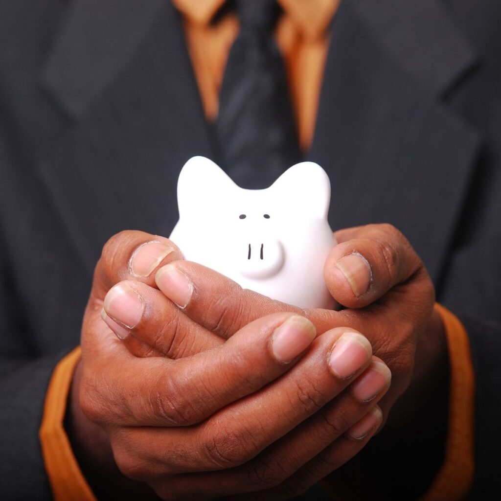 a man holding a piggy bank at the camera with his hands