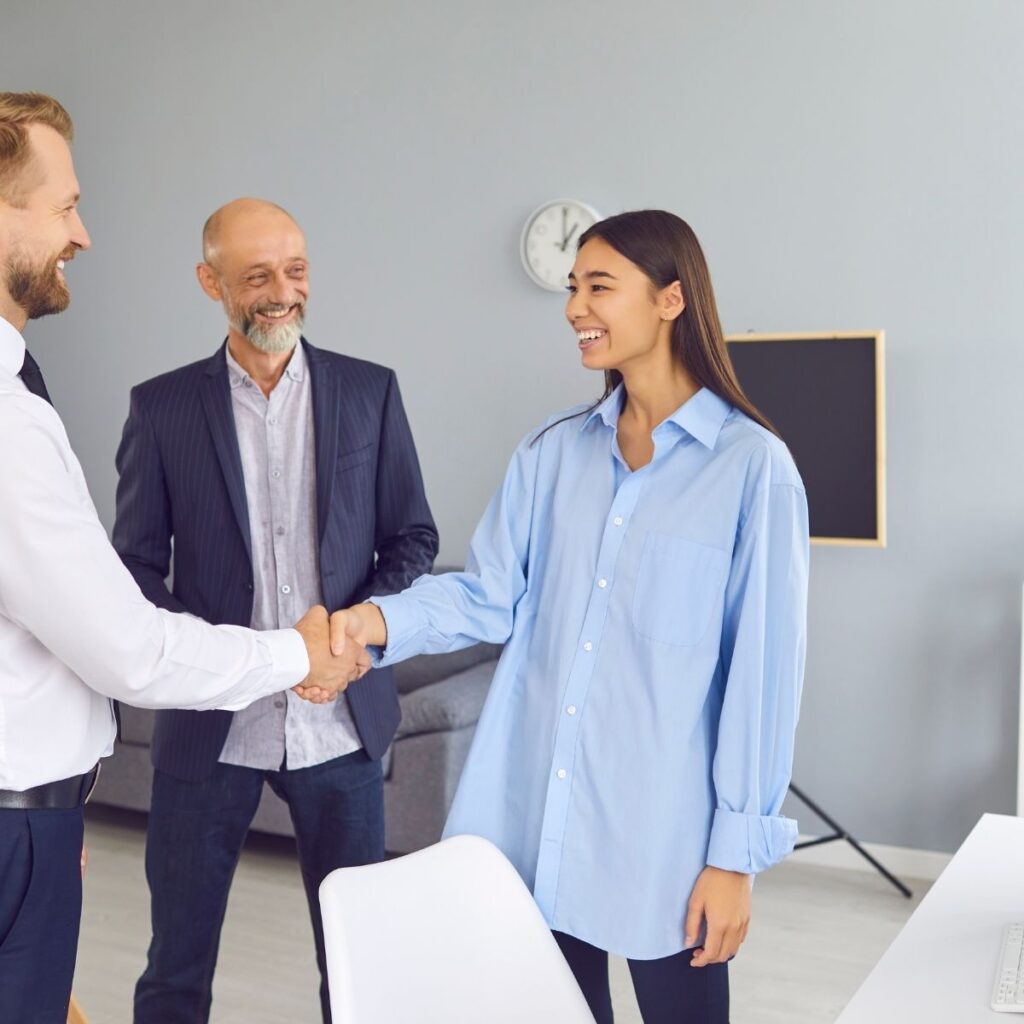 a woman shaking hands with a man in an office
