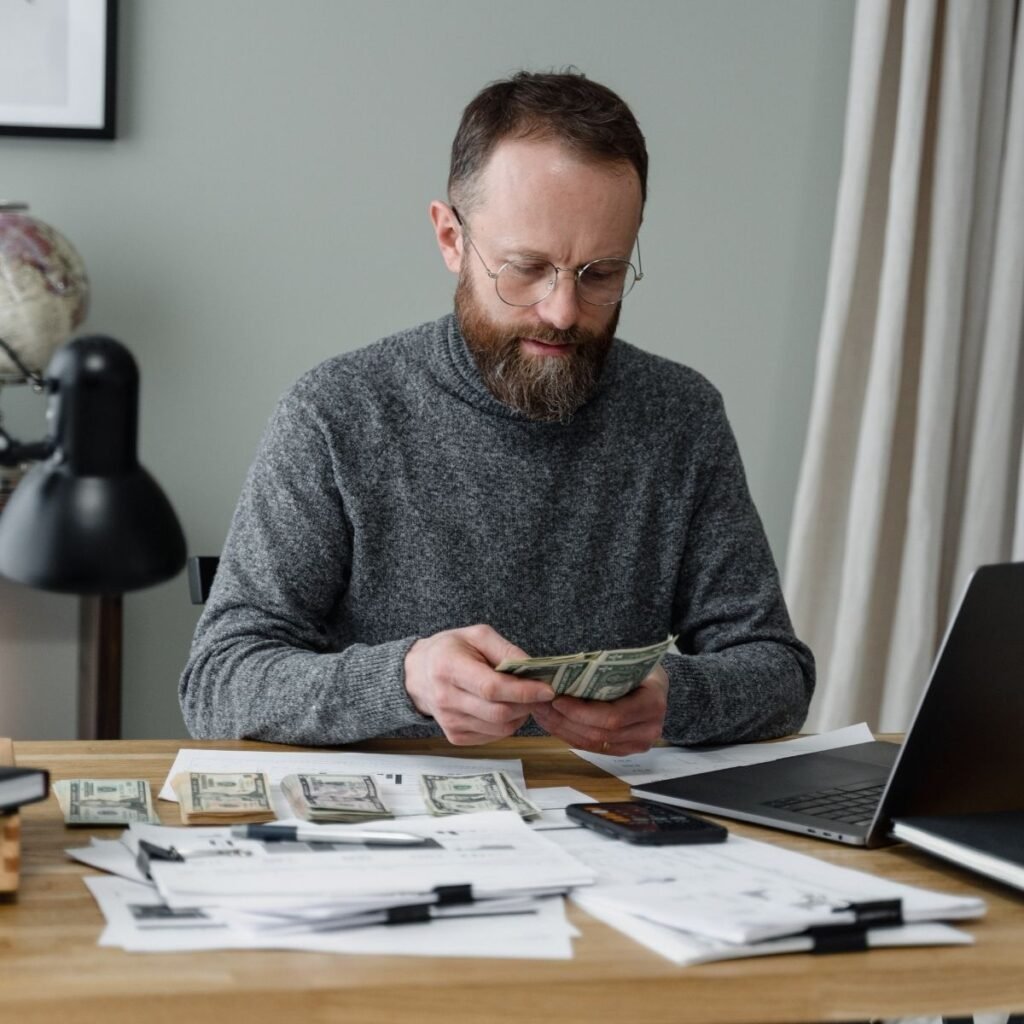 a man putting money in piles on a desk