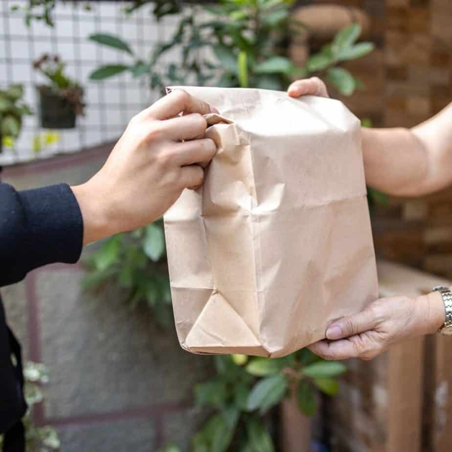 hands delivering a paper bag of goods