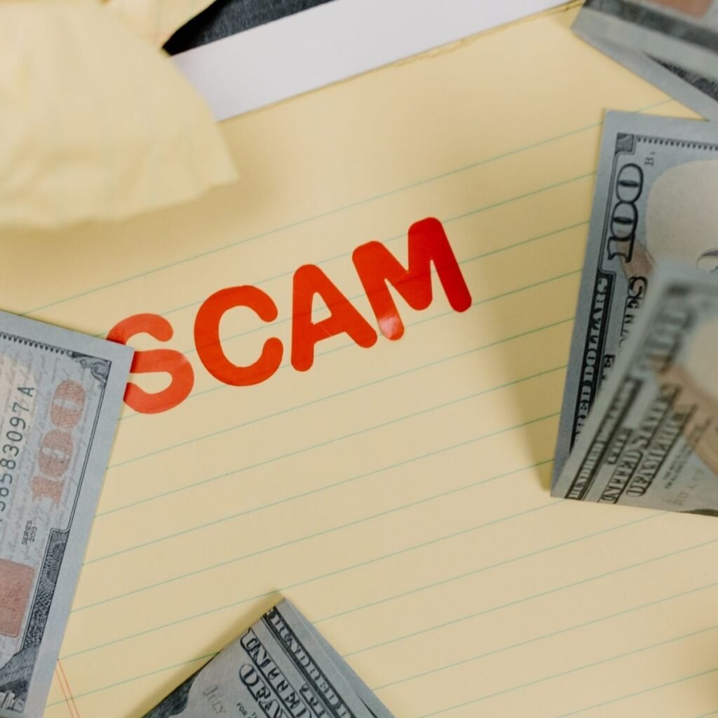 the words "scam" typed on yellow paper with money around it