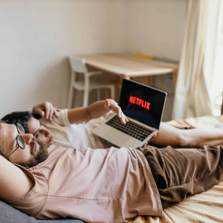 2 people lying in bed watching netflix on a laptop