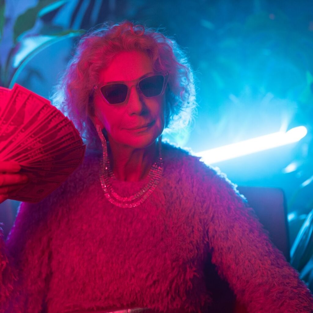 an old woman holding up cash in a dimly lit club