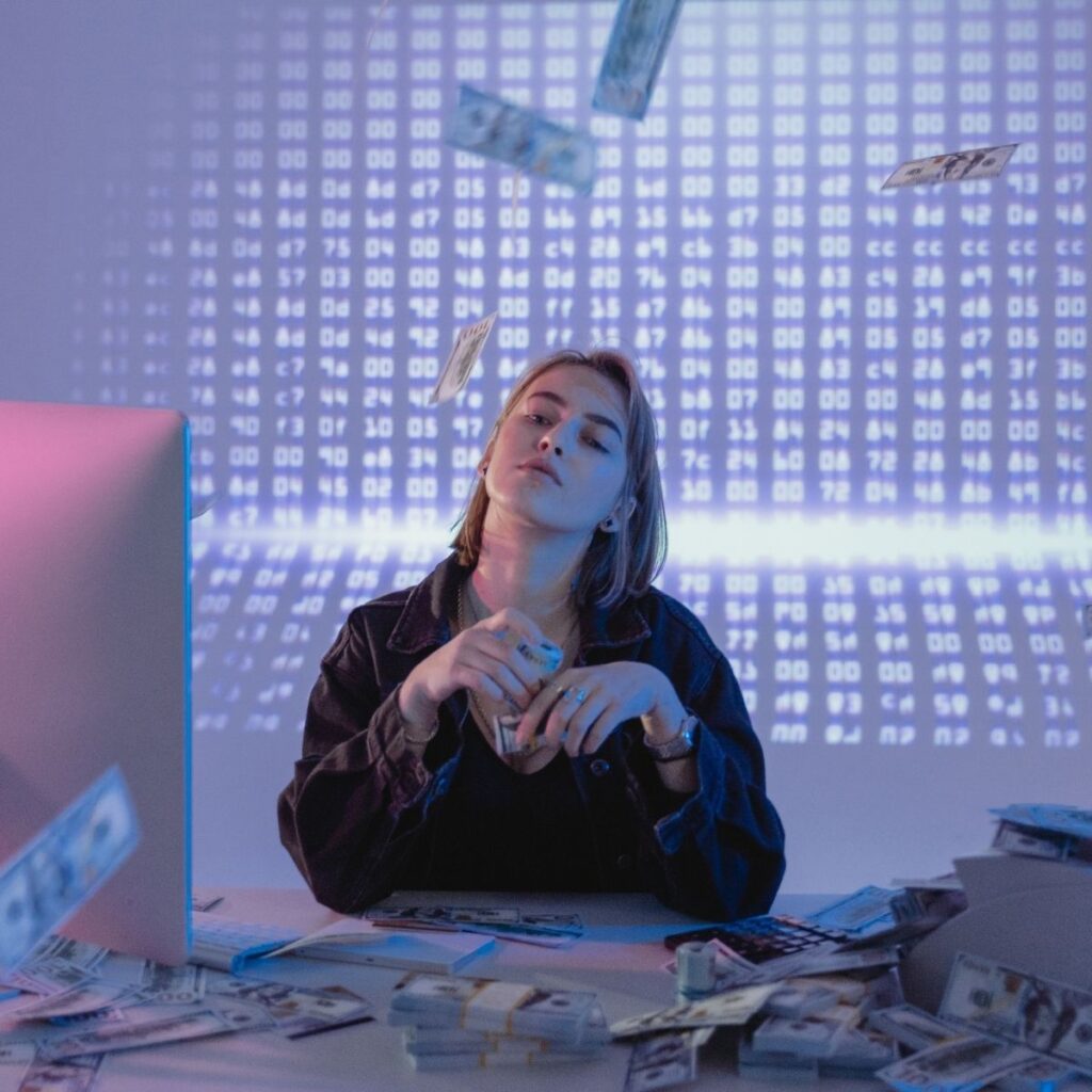 a woman throwing money in the air sitting at a desk