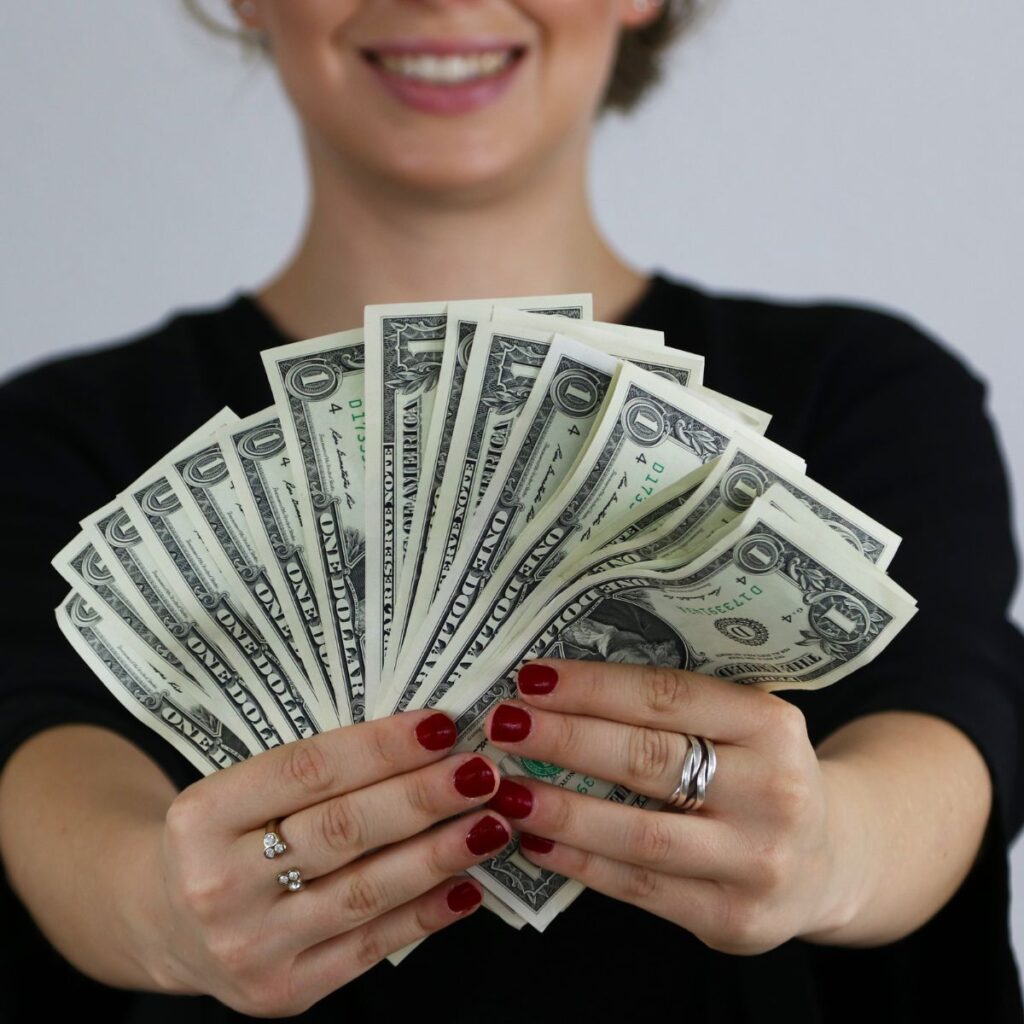 a woman fanning out money in front of the camera